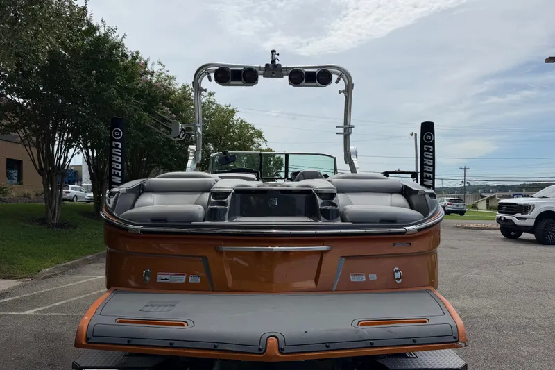 Slide: The Image of 2018 MasterCraft X26 boat with orange exterior and spacious seating, parked outdoors. - 7