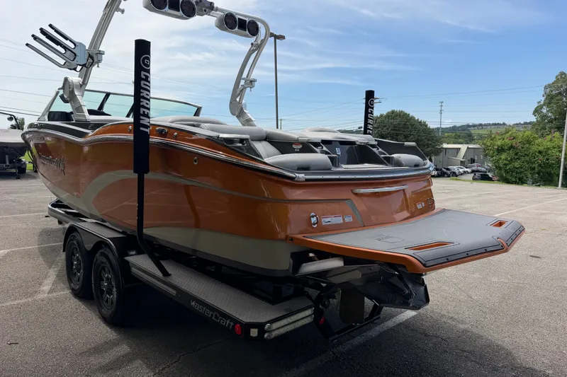 Slide: The Image of 2018 MasterCraft X26 boat on trailer, orange exterior, parked outdoors. - 6