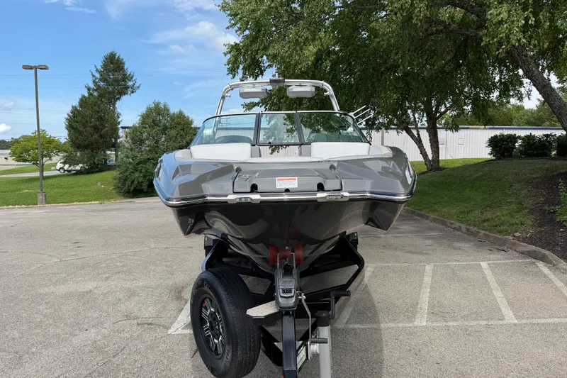 Slide: The Image of 2018 MasterCraft X26 boat on trailer in parking lot, surrounded by trees. - 3