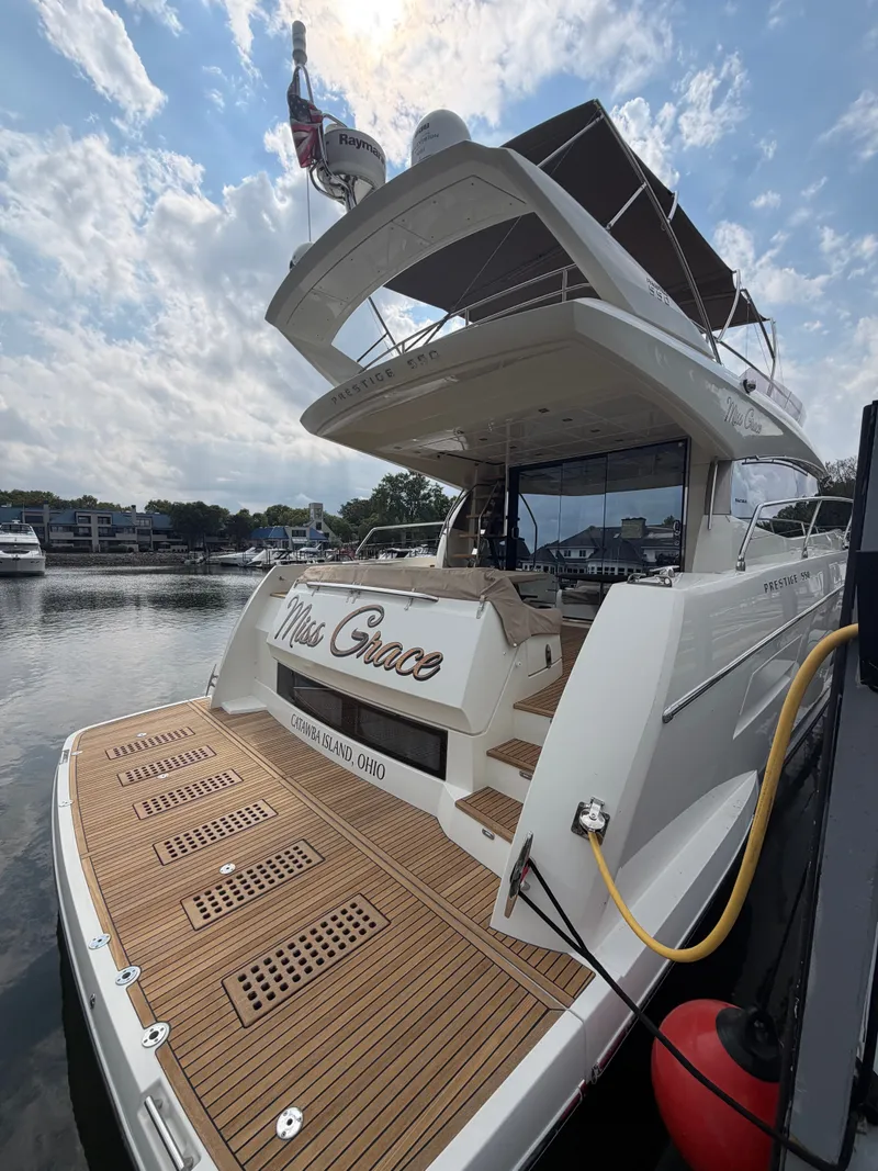Slide: The Image of A luxury yacht with a wooden deck, lounge chairs, and a covered upper deck, docked in a harbor. - 2