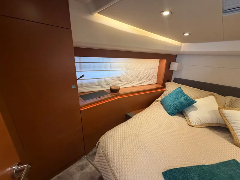 Slide: The Image of The cabin of a 2015 Prestige 550 with a cozy bed and elegant wood finish. - 27