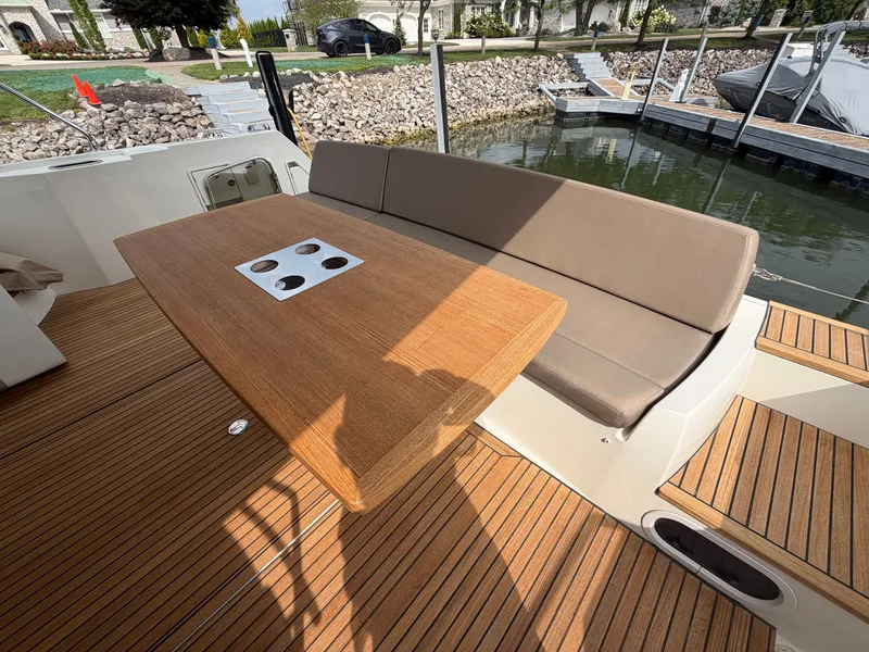 Slide: The Image of A sleek wooden table with cup holders on a boat, surrounded by a cushioned bench seat. - 8