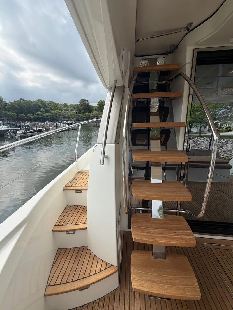 Slide: The Image of An elegant staircase with wooden steps leads to an upper deck. The background shows water and trees. - 9