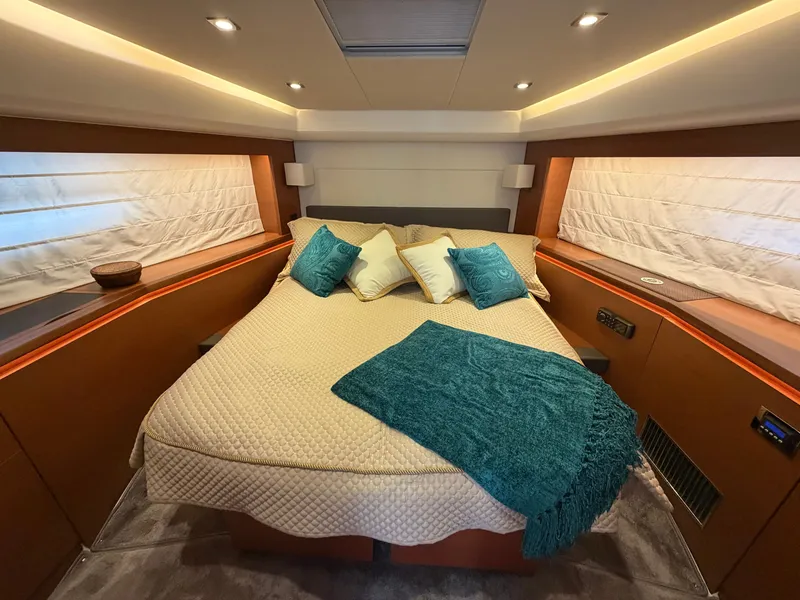 Slide: The Image of Luxurious cabin of the 2015 Prestige 550 with a large bed, pillows, and blanket. - 26