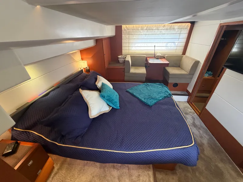 Slide: The Image of Luxurious cabin with a large bed, blue pillows, and a seating area with a table. - 36