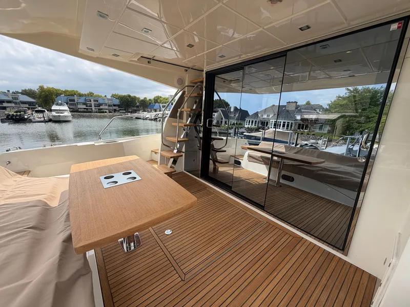 Slide: The Image of The 2015 Prestige 550 features an elegant aft deck with a wooden table and marina view. - 6