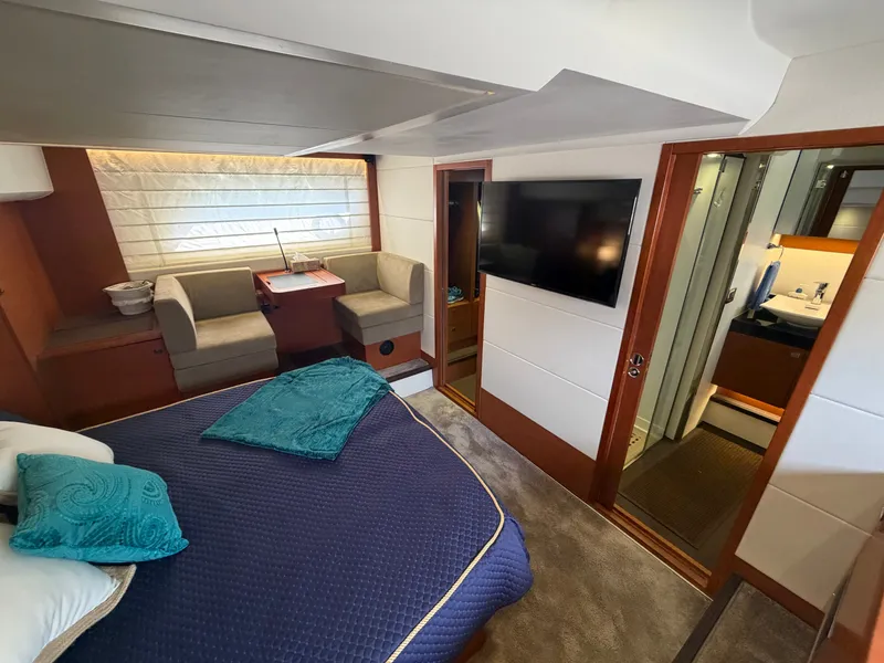 Slide: The Image of Luxurious cabin with double bed, seating area, TV, and adjoining bathroom on a Prestige 550 yacht. - 37