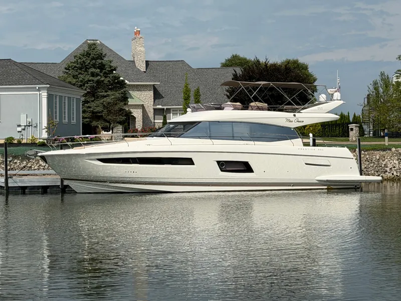 The Image of A 2015 Prestige 550 yacht docked in calm waters, with elegant houses in the background. - 0