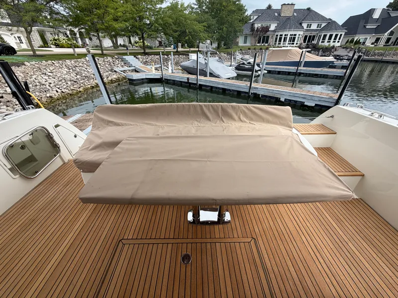 Slide: The Image of The 2015 Prestige 550 features a spacious teak deck with a large beige bench seat. - 11