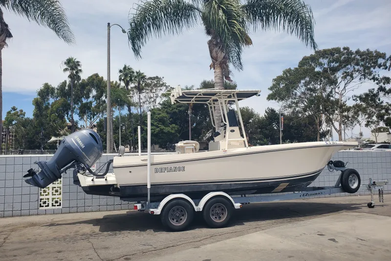 Slide: The Image of 2022 Defiance Commander 220 EX boat on trailer, parked near palm trees. - 2