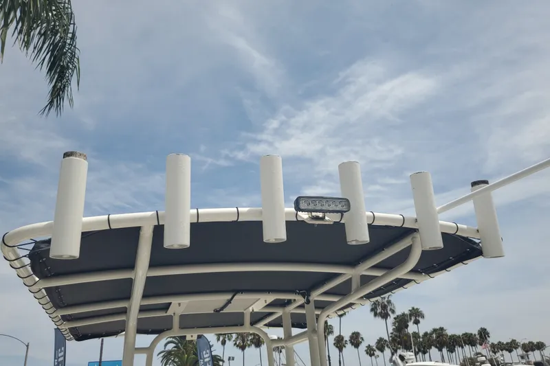 Slide: The Image of T-top of 2022 Defiance Commander 220 EX boat with rod holders under a cloudy sky. - 14