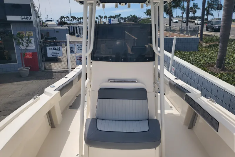 Slide: The Image of 2022 Defiance Commander 220 EX boat interior with seating and console, docked near palm trees. - 6