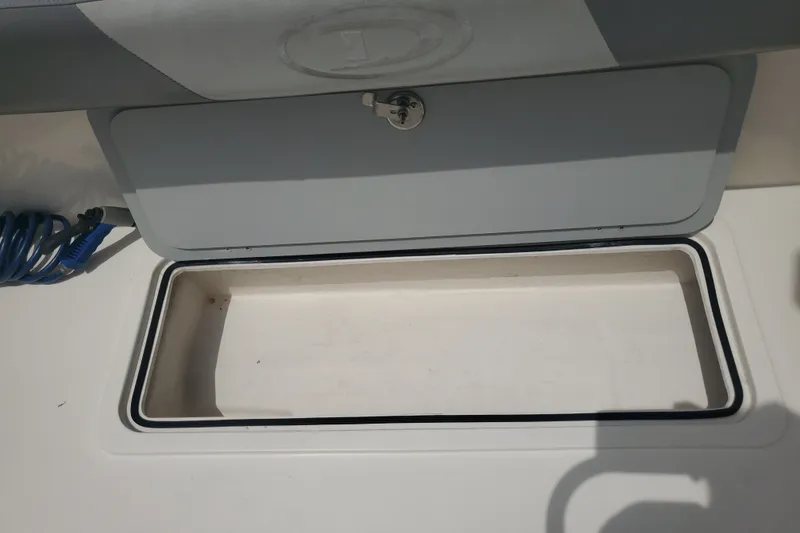 Slide: The Image of An open storage compartment on a boat with a gray lid and a blue rope nearby. - 20