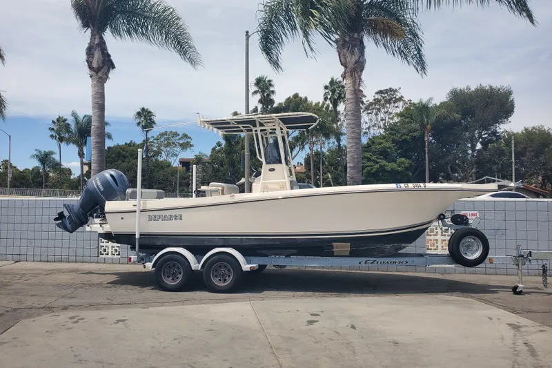 Slide: The Image of 2022 Defiance Commander 220 EX boat on trailer, parked near palm trees. - 1