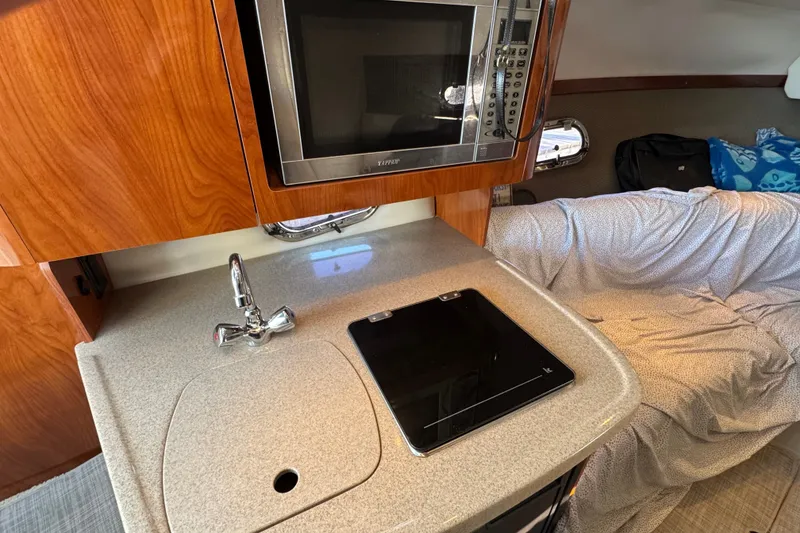 Slide: The Image of 2008 Four Winns V248 cabin interior with kitchenette, featuring a microwave and stovetop. - 14