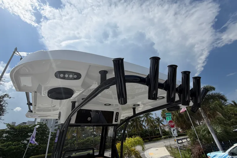 Slide: The Image of 2027 Sea Pro 262 DLX boat with rod holders and canopy under a partly cloudy sky. - 23