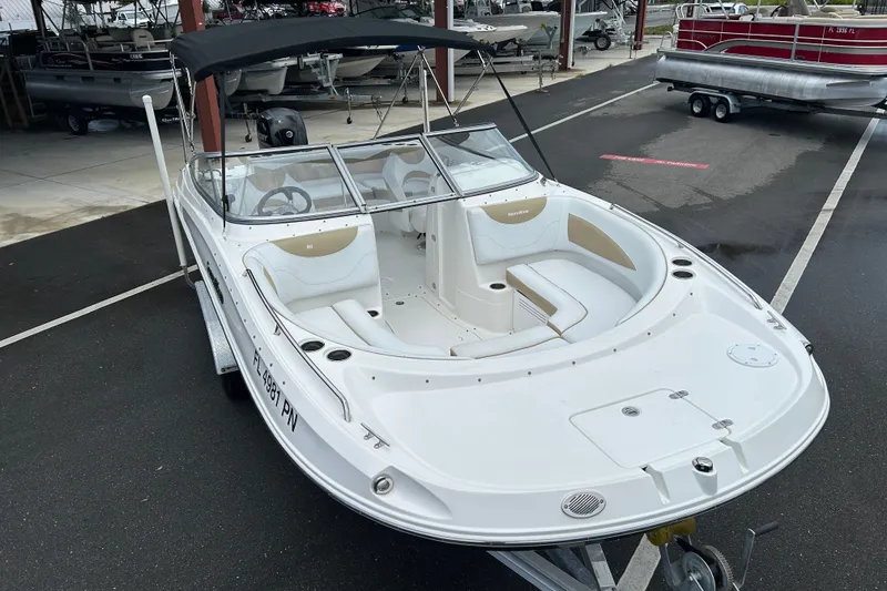 Slide: The Image of 2013 SouthWind 212 SD boat with white seating and black canopy in a marina. - 6