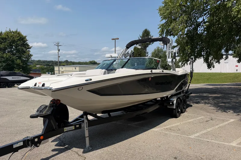 Slide: The Image of 2018 MasterCraft X46 boat on trailer in parking lot, sunny day. - 2
