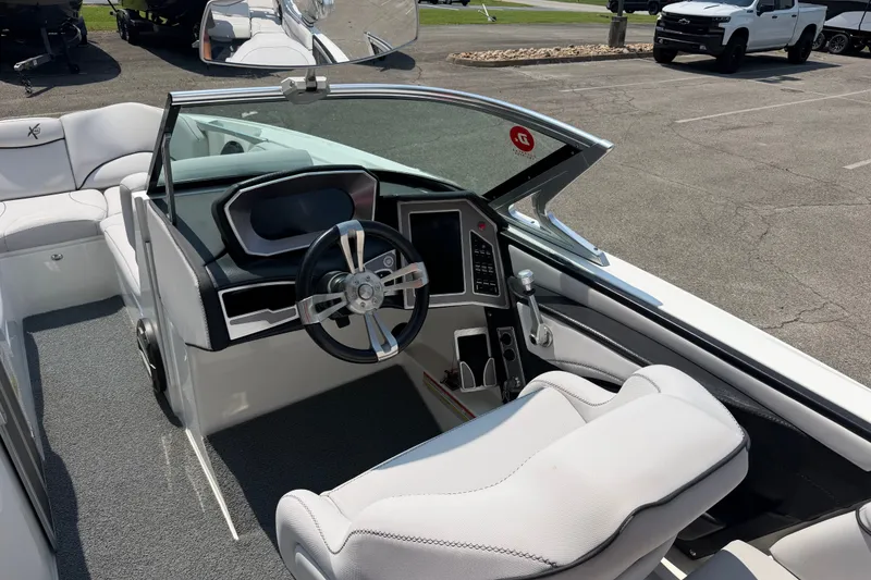 Slide: The Image of 2018 MasterCraft X46 boat interior with steering wheel and dashboard in a parking lot. - 12