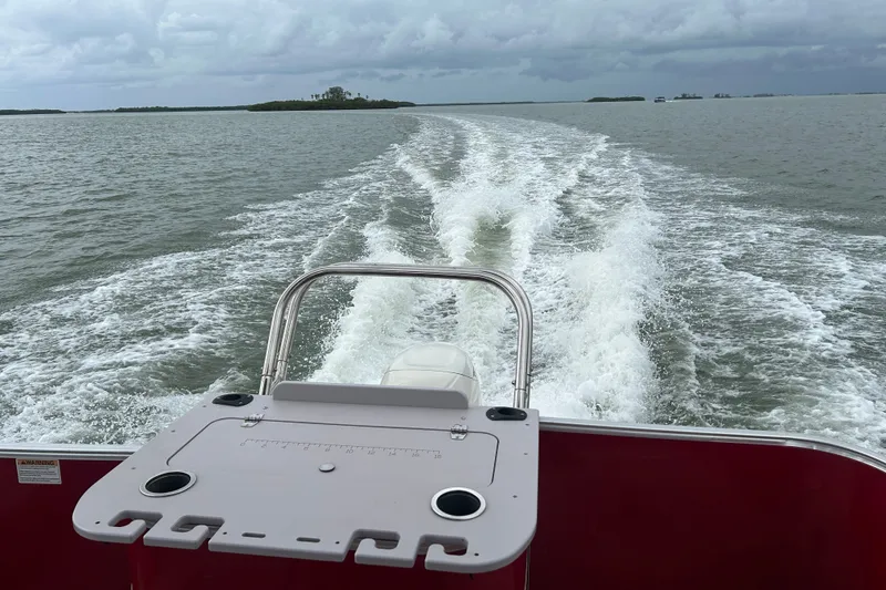 Slide: The Image of 2013 Sylvan Mirage Fish 8520 CNF cruising on open water, leaving a wake behind. - 21