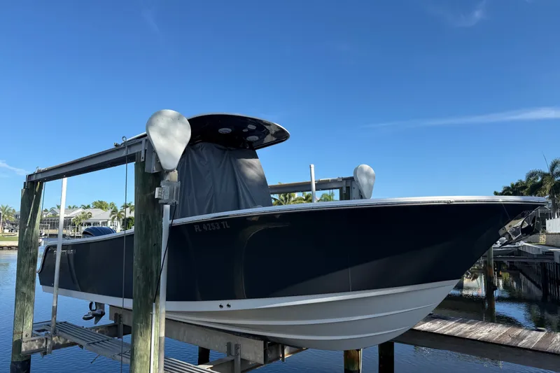 The Image of 2023 Sportsman Heritage 241 Center Console boat on lift, docked by waterfront. - 0