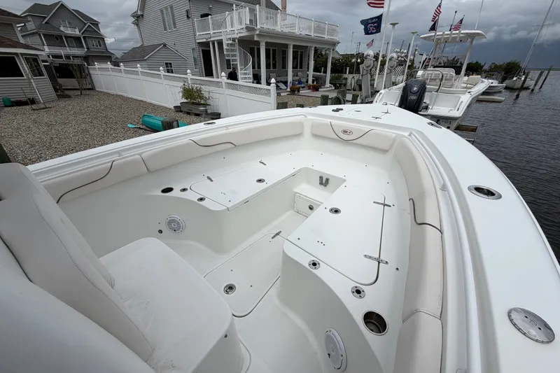 Slide: The Image of 2019 Sea Hunt Gamefish 25 boat docked near waterfront homes under cloudy skies. - 22