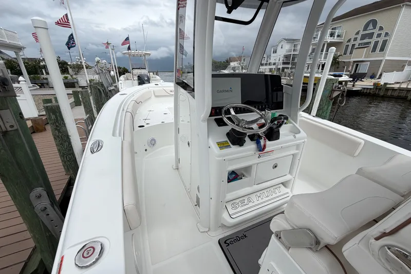 Slide: The Image of 2019 Sea Hunt Gamefish 25 boat docked, featuring a Garmin navigation system and comfortable seating. - 20