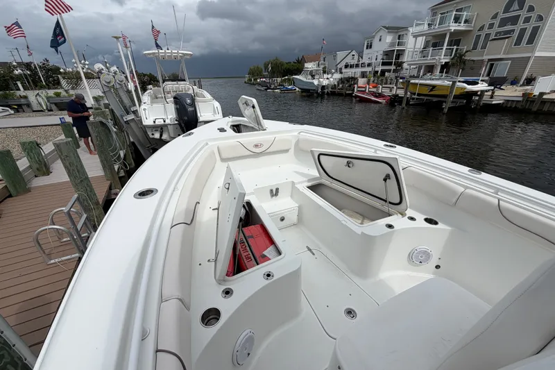 Slide: The Image of 2019 Sea Hunt Gamefish 25 boat docked, open storage compartments, cloudy sky, waterfront homes. - 25