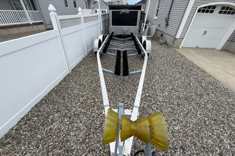 Slide: The Image of Boat trailer for 2019 Sea Hunt Gamefish 25 on gravel driveway near white fence. - 34