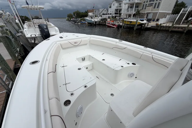 Slide: The Image of 2019 Sea Hunt Gamefish 25 boat docked near waterfront homes under cloudy skies. - 21