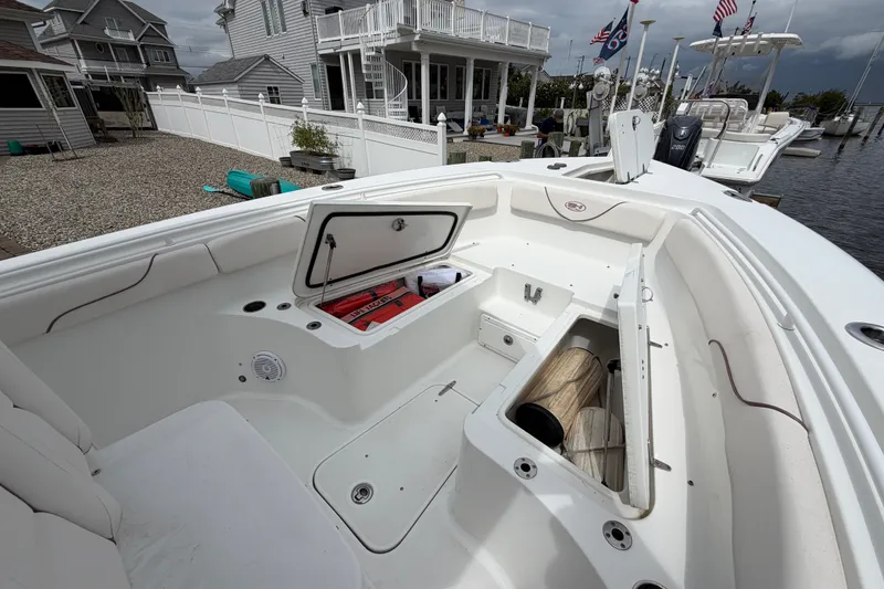 Slide: The Image of 2019 Sea Hunt Gamefish 25 boat with open storage compartments at a dockside location. - 26