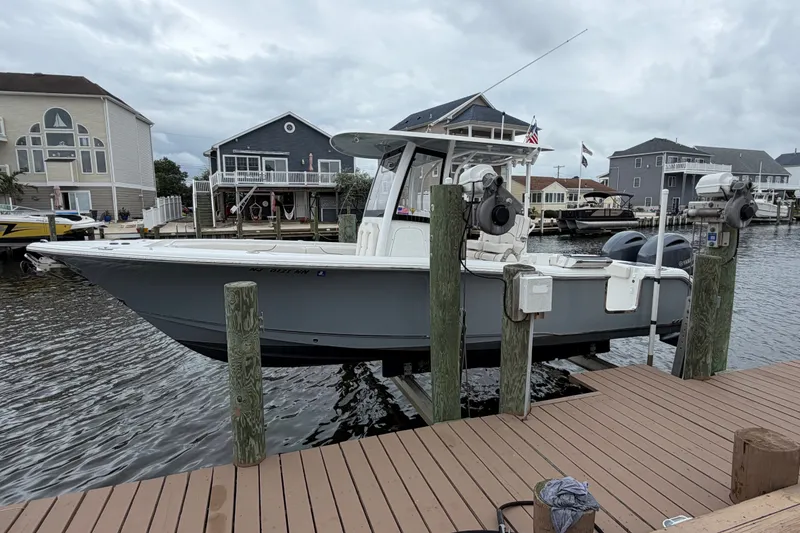The Image of 2019 Sea Hunt Gamefish 25 boat docked at a marina with waterfront homes. - 0