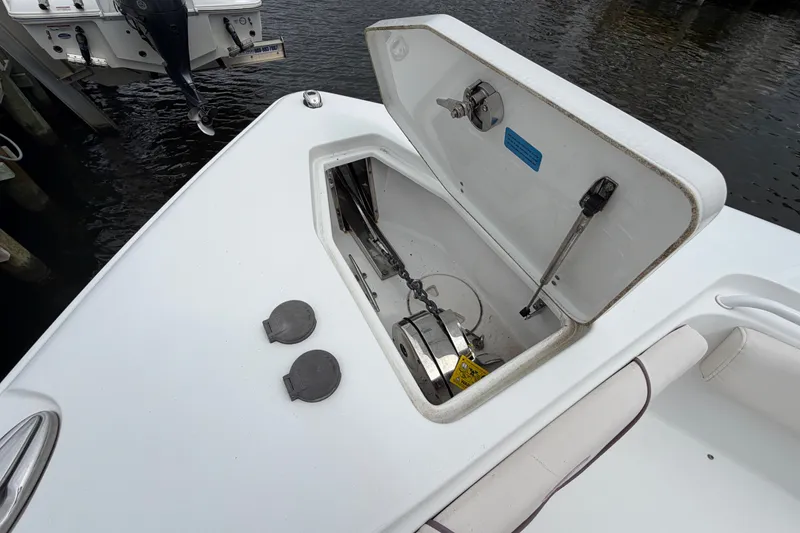 Slide: The Image of 2019 Sea Hunt Gamefish 25 boat anchor compartment open, showing chain and mechanism. - 24