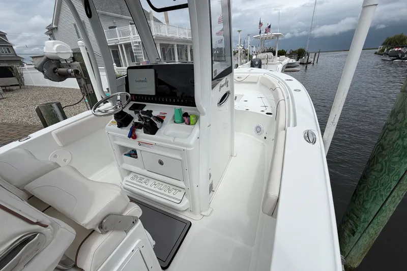 Slide: The Image of 2019 Sea Hunt Gamefish 25 boat interior with Garmin navigation, docked by waterfront homes. - 19