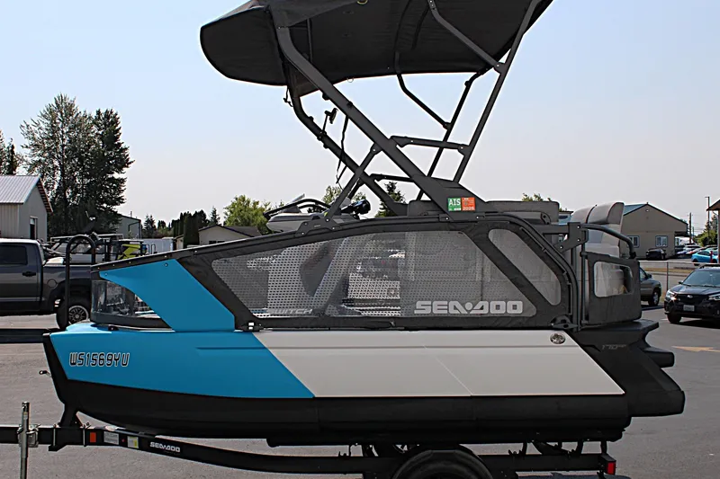 Slide: The Image of 2023 Sea-Doo Switch Sport Compact pontoon boat with blue and white design on trailer. - 9