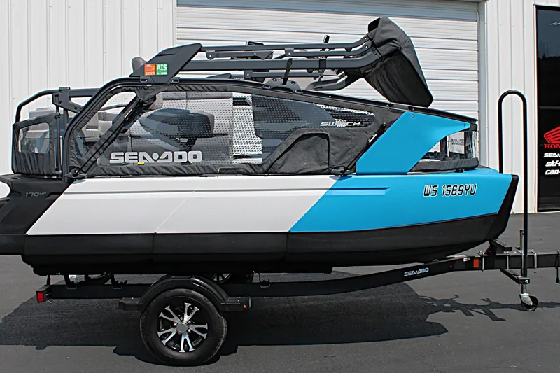 Slide: The Image of 2023 Sea-Doo Switch Sport Compact on trailer, blue and white design, parked outdoors. - 14