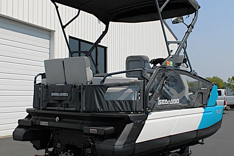 Slide: The Image of 2023 Sea-Doo Switch Sport Compact boat parked near a white building. - 6