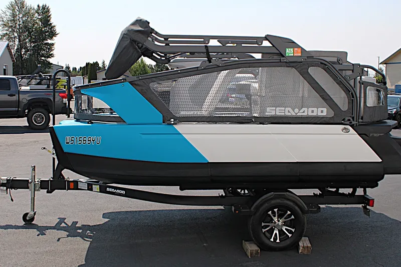 Slide: The Image of 2023 Sea-Doo Switch Sport Compact on trailer, side view, blue and white design. - 17