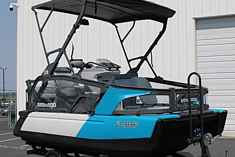Slide: The Image of 2023 Sea-Doo Switch Sport Compact boat with canopy, parked outside a building. - 4