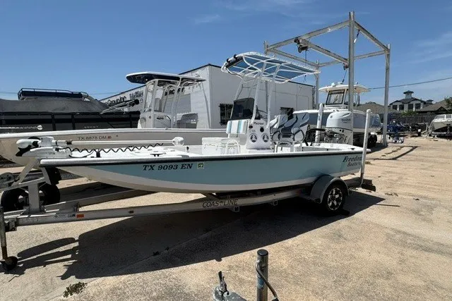 Slide: The Image of 2019 Freedom Boats 18' Patriot on trailer, parked outdoors under clear blue sky. - 18