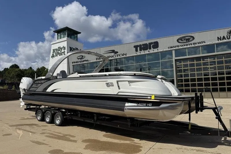 The Image of 2024 Bennington 30 QXFBAX2 pontoon boat on trailer at dealership under blue sky. - 1