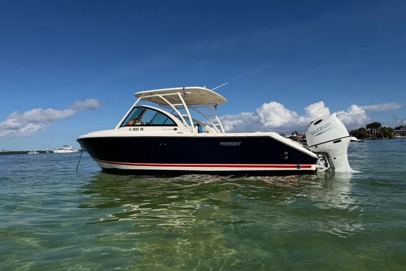 Slide: The Image of 2013 Pursuit DC 265 Dual Console boat on clear water under blue sky. - 1
