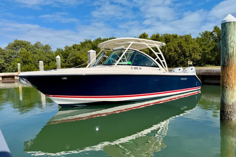 The Image of 2013 Pursuit DC 265 Dual Console boat docked on calm water under a clear blue sky. - 0