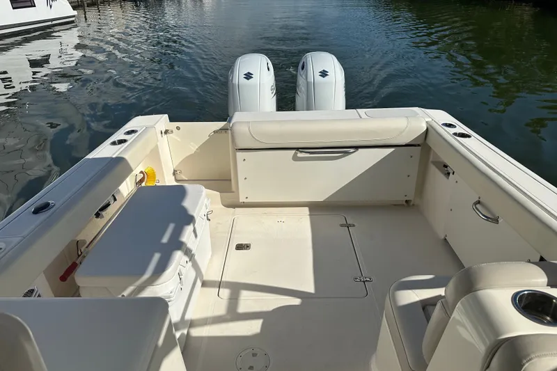 Slide: The Image of 2013 Pursuit DC 265 Dual Console boat interior with twin engines on calm water. - 11