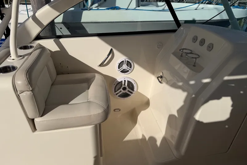 Slide: The Image of 2013 Pursuit DC 265 Dual Console interior with beige seating and cup holders. - 15