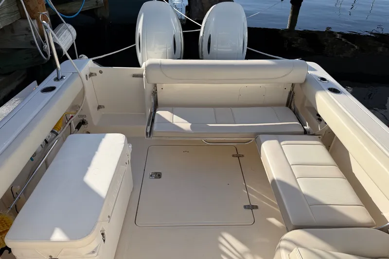 Slide: The Image of 2013 Pursuit DC 265 Dual Console boat interior with beige seating and storage compartments. - 12