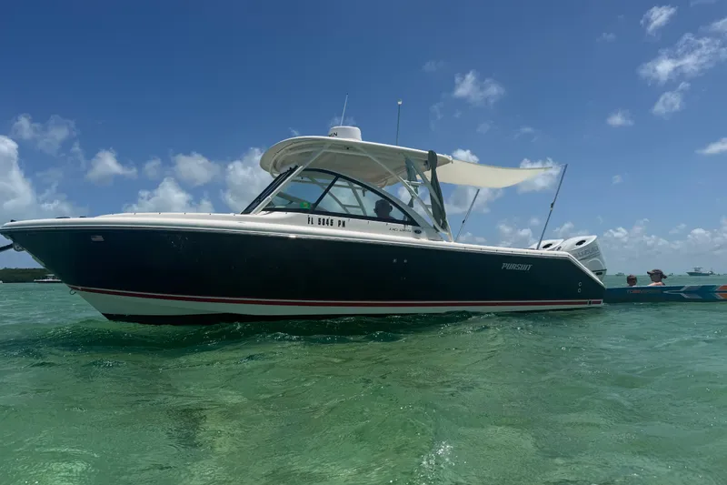 Slide: The Image of 2013 Pursuit DC 265 Dual Console boat on clear water under blue sky. - 5