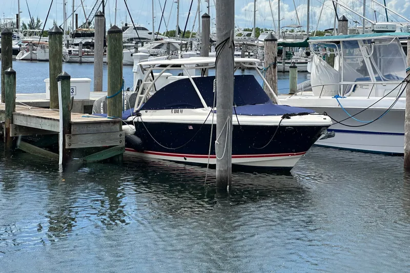 Slide: The Image of 2013 Pursuit DC 265 Dual Console boat docked at marina, surrounded by other vessels. - 6