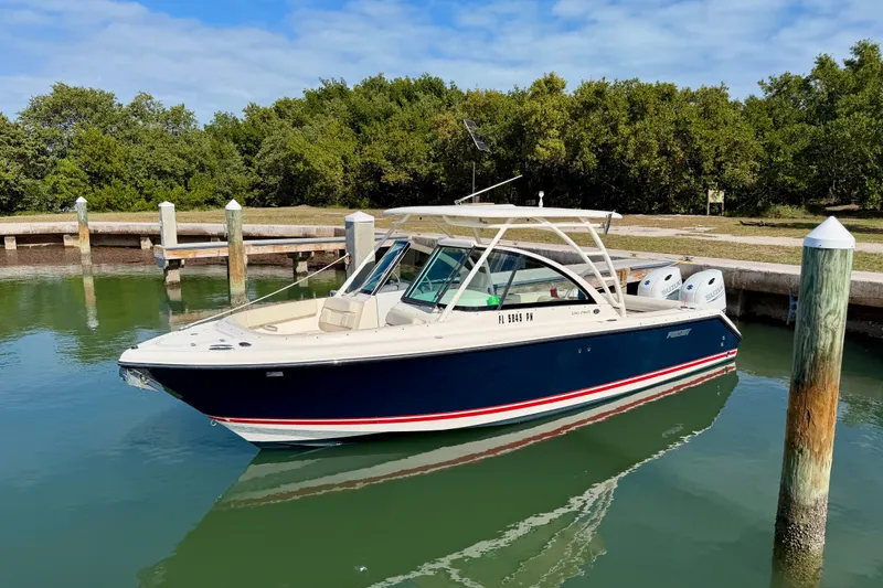 Slide: The Image of 2013 Pursuit DC 265 Dual Console boat docked in calm waters. - 2