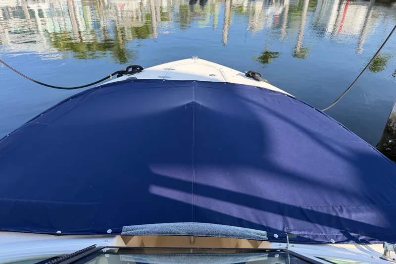 Slide: The Image of 2013 Pursuit DC 265 Dual Console boat with blue cover docked by calm water. - 21